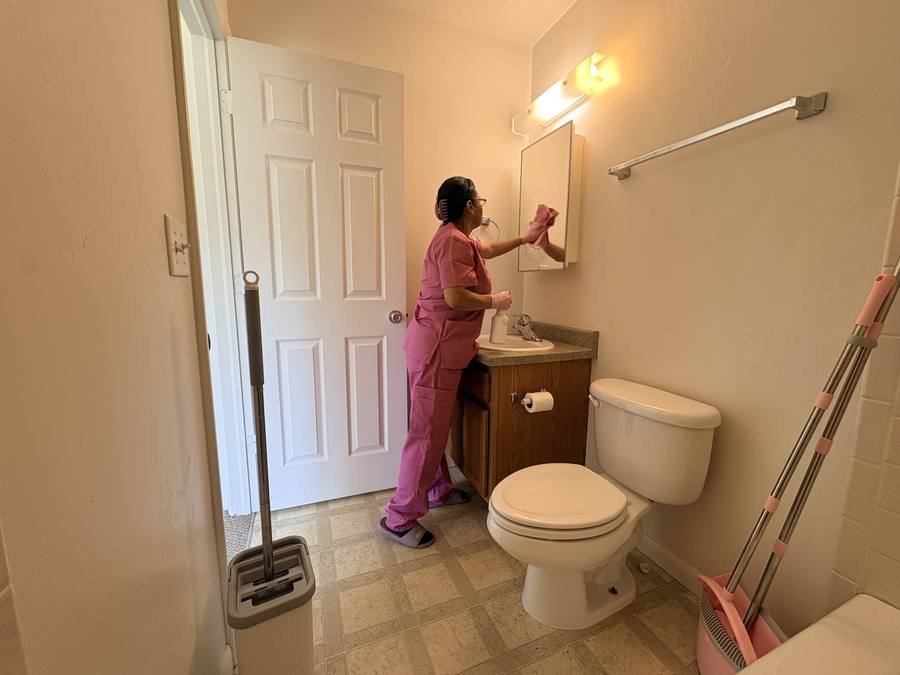 Cleaner detailing a bathroom vanity and mirror during a residential clean