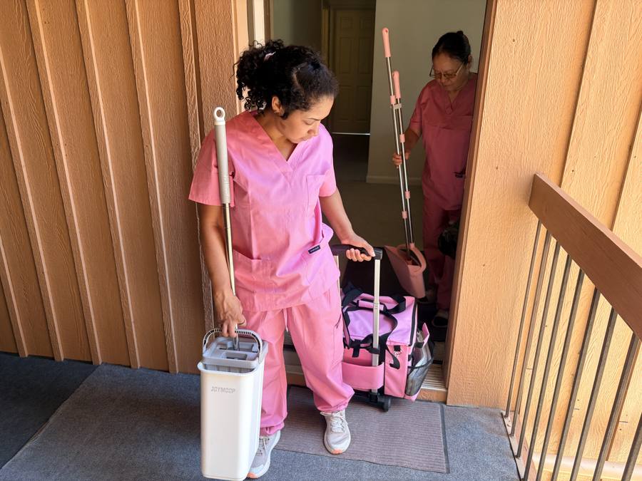 Cleaning team heading into a home with mop and supply kit
