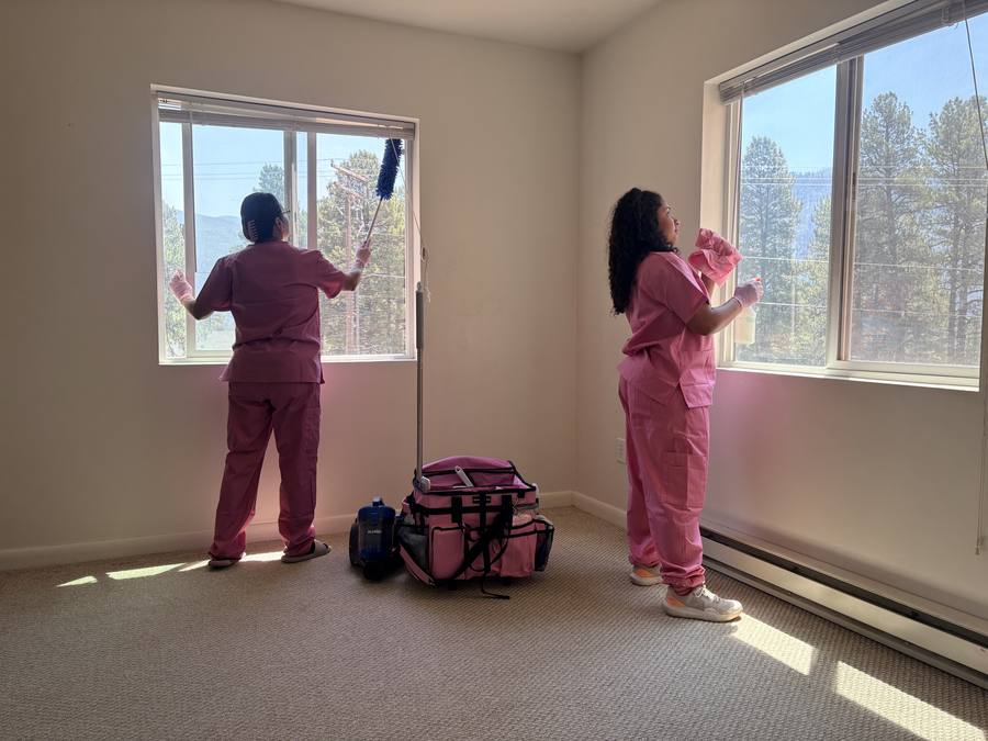 Two Animas Cleaning team members washing windows in a sunny Durango living room