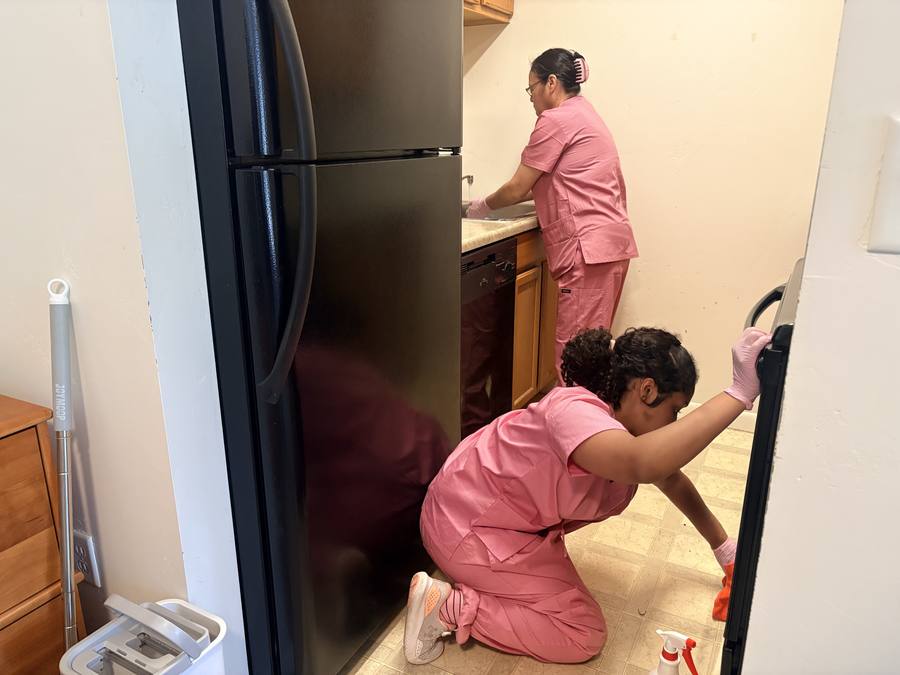 Two cleaners deep cleaning a kitchen, including floors and appliances